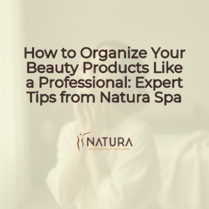 A woman with glowing skin, with short hair and minimalist style, smiling confidently and touching her face. The background is softly blurred with warm, natural tones.