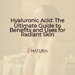 A woman in a towel wrap in a spa setting, with natural glowing skin, relaxed pose, and a genuine confident smile. The background is softly blurred with warm, diffused lighting. She's touching her face gently, showcasing a natural skincare routine.