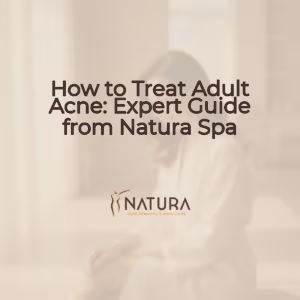 A woman with glowing skin touching her face, set against a blurred warm beige background, evoking a spa-like feel.