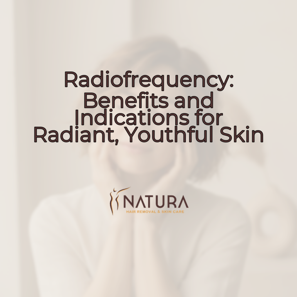 A woman with short hair and glowing skin, smiling warmly, touches her face. The background is softly blurred with warm beige and brown tones.