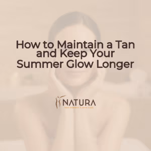 A woman with glowing skin, relaxed in a spa pose, touching her face with a genuine confident smile. Soft diffused lighting illuminates the scene, with a blurred natural background.
