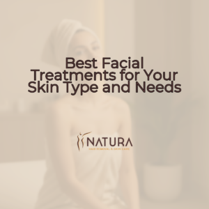 A woman in a towel wrap, in a spa setting, with natural glowing skin and a relaxed pose, touching her face with a confident smile.