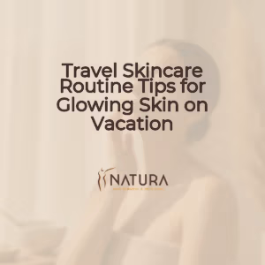 A woman with radiant, glowing skin, captured in a relaxed spa-like pose, her hand gently touching her face. She has a genuine, confident smile, illuminated by soft, diffused lighting. The background is softly blurred, evoking a luxurious and natural aesthetic.